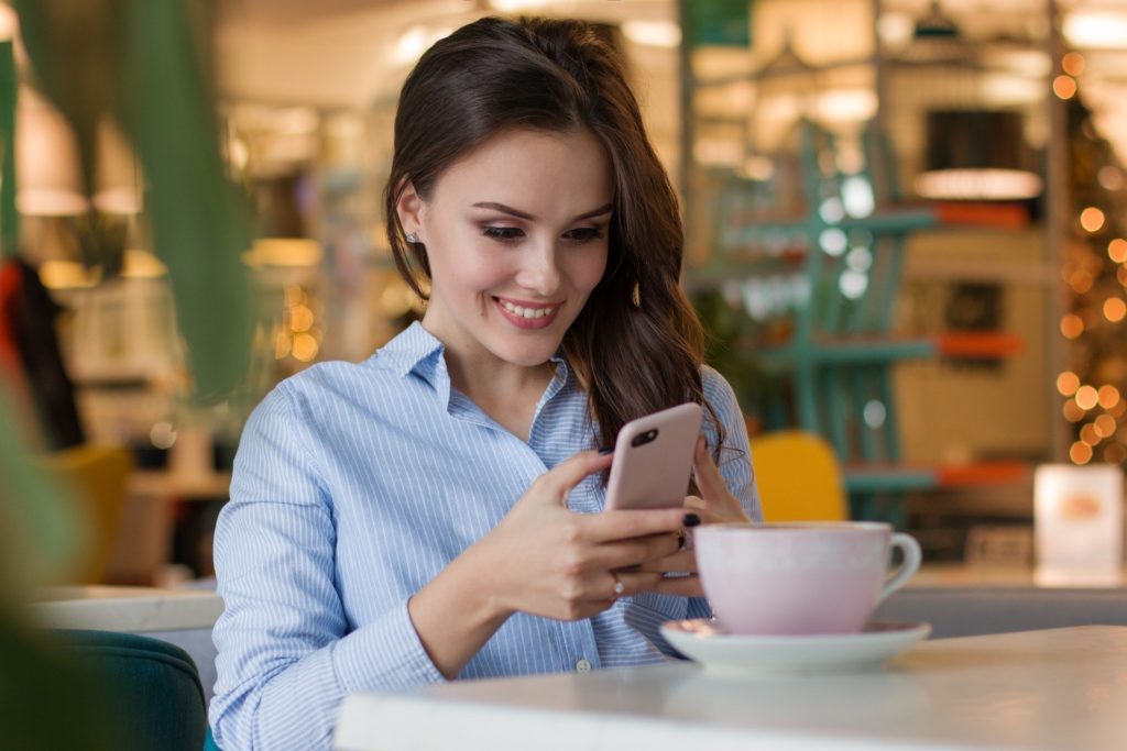 Happy woman with smartphone at restaurant